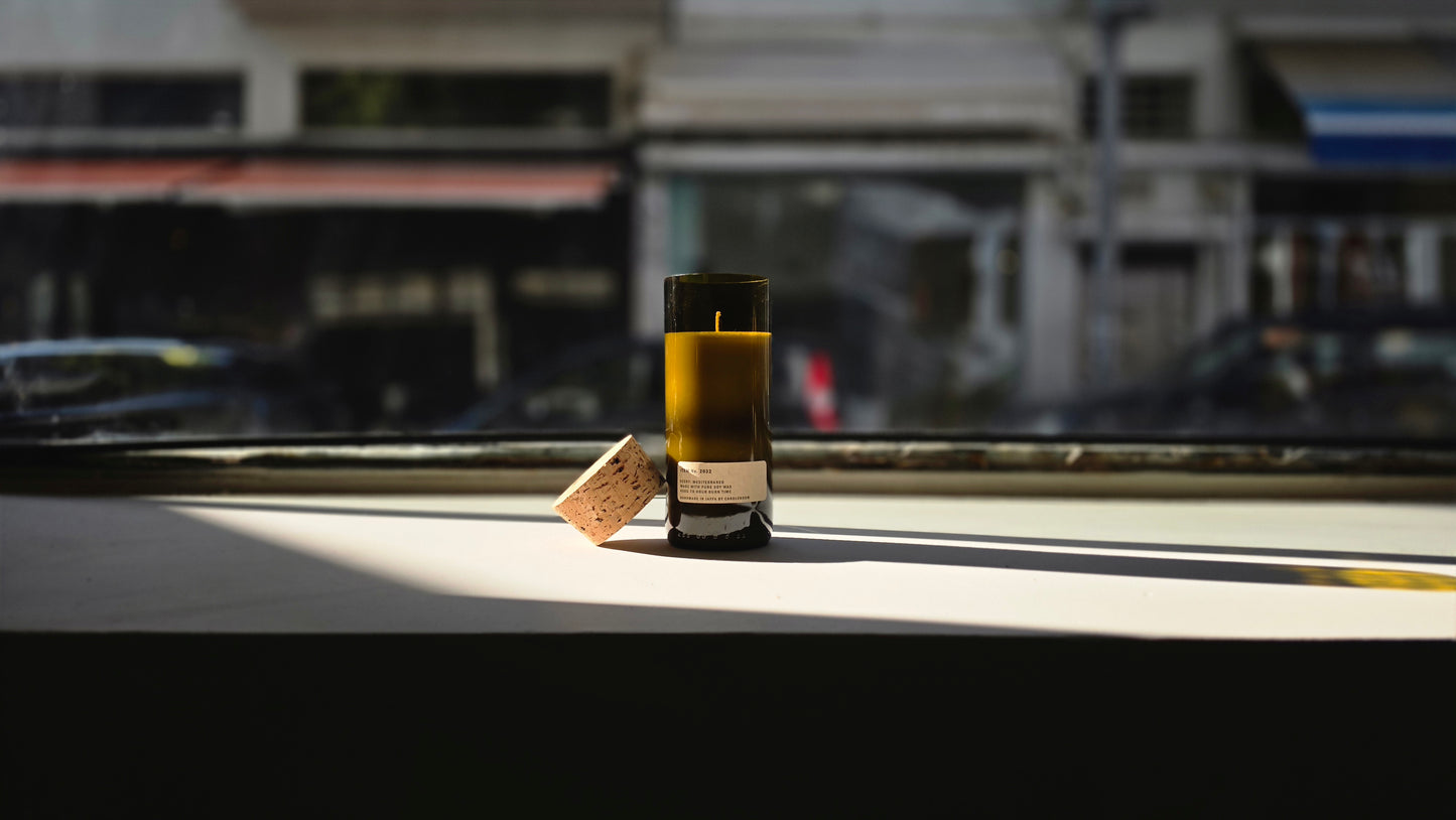 Mediterraneo Loft Botanical Candle in a recycled wine bottle with cork, natural soy wax, golden sunlight on windowsill