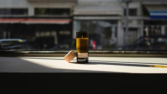Mediterraneo Loft Botanical Candle in a recycled wine bottle with cork, natural soy wax, golden sunlight on windowsill
